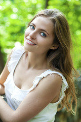 Young beautiful woman in green dress posing outdoors in sunny we