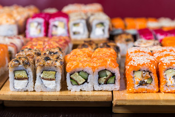 assorted sushi and rolls on wood board in dark light