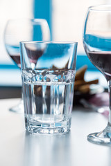 glass with water and wineglasses on blue window background