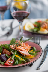 salad with salmon and verdure in plate on table with blue chair