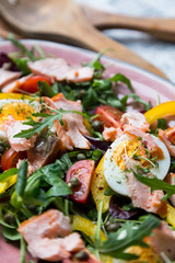 salad with salmon and verdure in pink plate on retro newspaper b