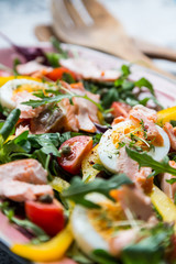 salad with salmon and verdure in pink plate on retro newspaper b