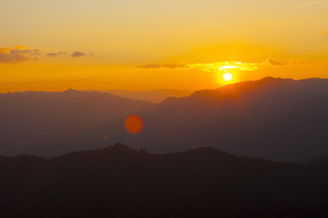 dramatic sky sun set over mountain with orange dramatic sky with lensflare