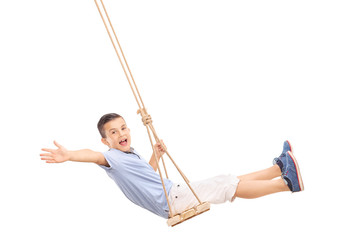Joyful little boy swinging on a swing - obrazy, fototapety, plakaty