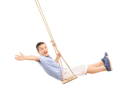 Joyful little boy swinging on a swing