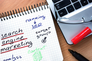 Notepad with words search engine marketing  on a wooden background