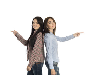 Two smiling girls pointing to opposite directions.
Two young women stay back to back and pointing hands into opposite directions on white background casually dressed jeans style