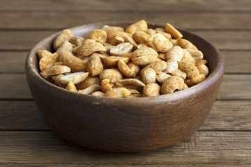 Spicy dry roasted peanuts in rustic wood bowl.