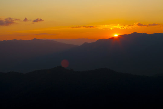 dramatic sky sun set over mountain with orange dramatic sky with lensflare