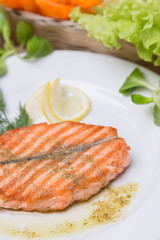 hot grilled salmon with garnish on white plate