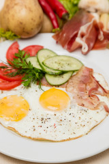 Fototapeta na wymiar bacon and eggs with garnish on white plate