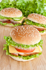three burger with meat and vegetables on wood plate