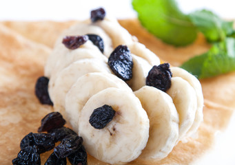 Rolled pancakes with banana and raisins