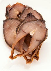 sliced smoked fish on plate on white