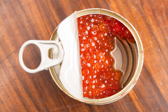 red caviar in bank with spoon on wood