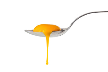 Raw egg yolk leaking from the spoon, isolated on white
