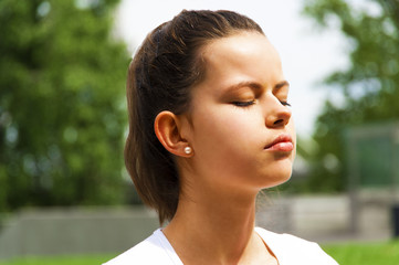 Young beautiful woman doing meditation in park.