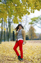 Young woman in fashion coat walking in autumn park