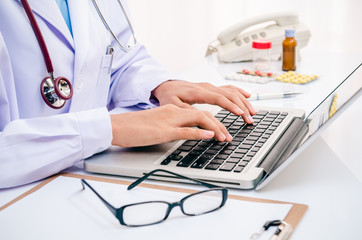 doctor typing information on the computer in office
