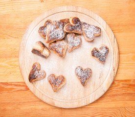 bakery hearts from split pastry with sugar powder on wooden
