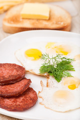 breakfast with fried eggs, sausage and toast on plate