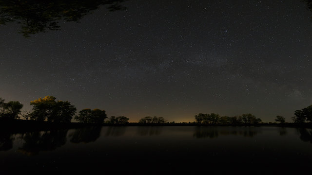Smooth surface of forest lake on a background of the night sky a