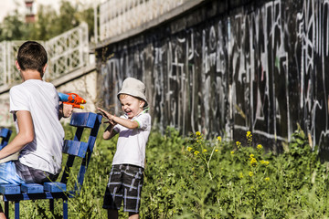 child and teenager playing in the street Water Gun