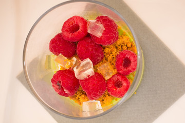 Dessert with raspberries under white plate in a glass