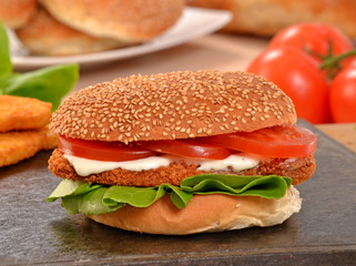 Hamburguesa de pollo e ingredientes sobre plancha caliente.