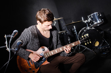 Man playing guitar in dark room