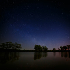 Naklejka na ściany i meble Smooth surface of forest lake on a background of the night sky a