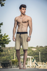 Young shirtless athletic man standing at the beach