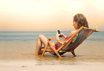 Young woman using her smartphone at the beach