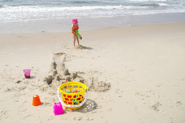 Jeune fille jouant à la plage dans le sable blanc.