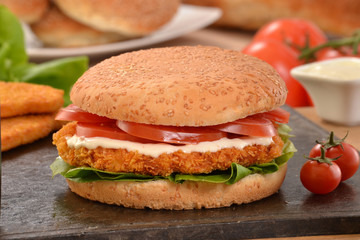 Hamburguesa de pollo e ingredientes sobre plancha caliente.