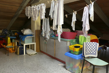 Attic with many throw things and clothes hung out to dry