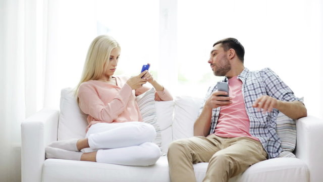 couple with smartphones texting at home