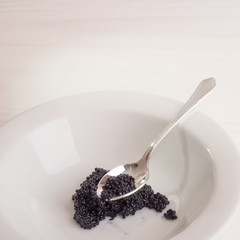 Silver Spoon and Caviar in White Bowl