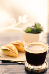 Breakfast (Sandwich croissant with cheese,ham and vegetable) and hot coffee in the morning,vintage color tone