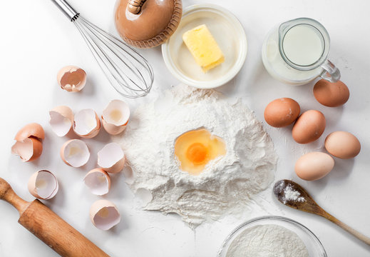 baking background with raw eggs,eggshell, sugar, flour , milk and butter