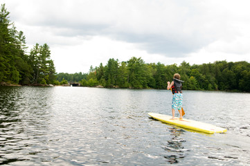 Fototapeta na wymiar young boy stand up paddle boarding