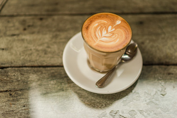 Art latte coffee with leaf pattern on wooden background