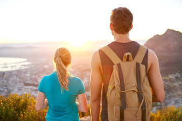 Guy and girl watching the sunrise while on a hike