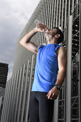 young sport man drinking water bottle after running training