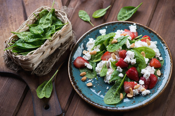 Spinach, strawberry and cheese salad on a dark wooden background
