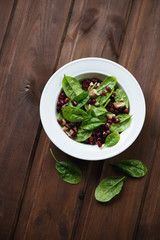 Salad with fresh spinach, pomegranate and walnuts, above view
