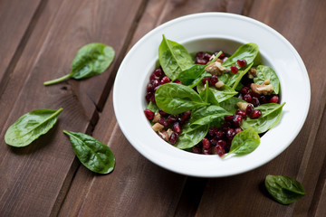 Spinach leaves, pomegranate seeds and walnuts salad, studio shot