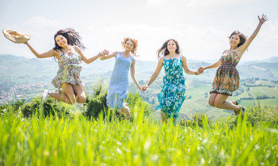 four girls jumping together in the nature