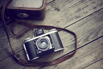 Old retro camera and belt bag (leather case) on vintage wooden boards abstract background