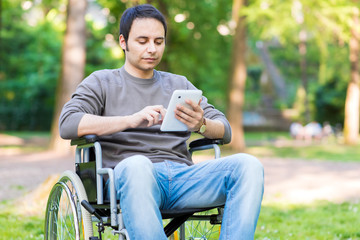 Disabled man using a tablet in a park